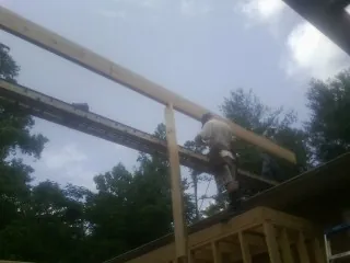Carpenter setting a ridge beam over a new addition frame — Ice Dam Removal by Roofing Brothers in Binger