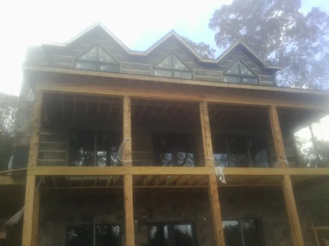Dormers and porch framing on a large log home under construction — Roof Coating work by our crew in Binger