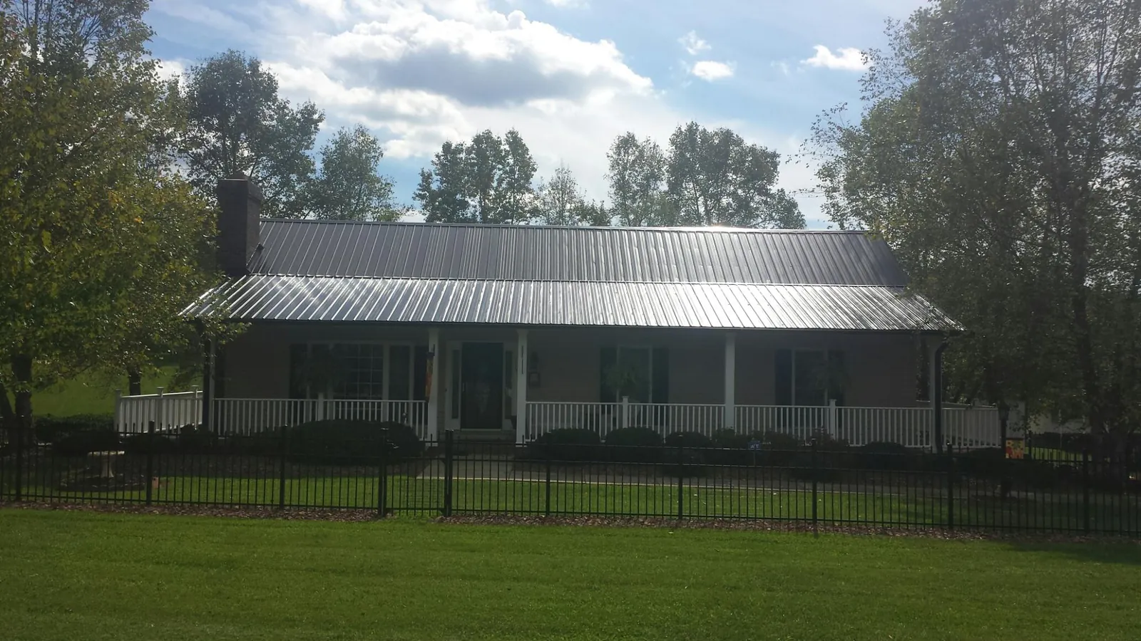 Gray metal roof on a brick ranch with a full width front porch — Gutter Guard Installation work by our crew in Binger